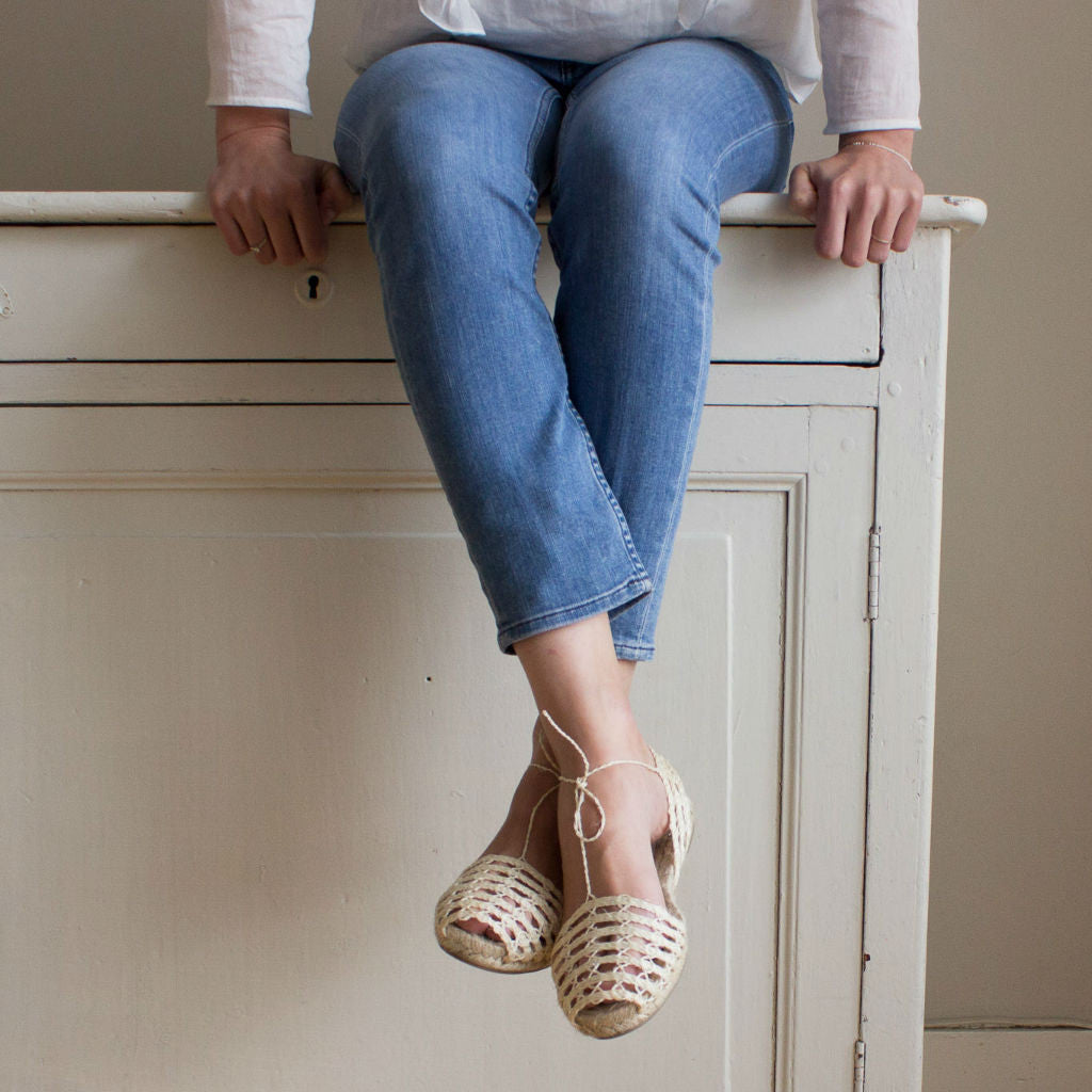 Model sitting on a chest with drawers wearing ibizan espadrilles